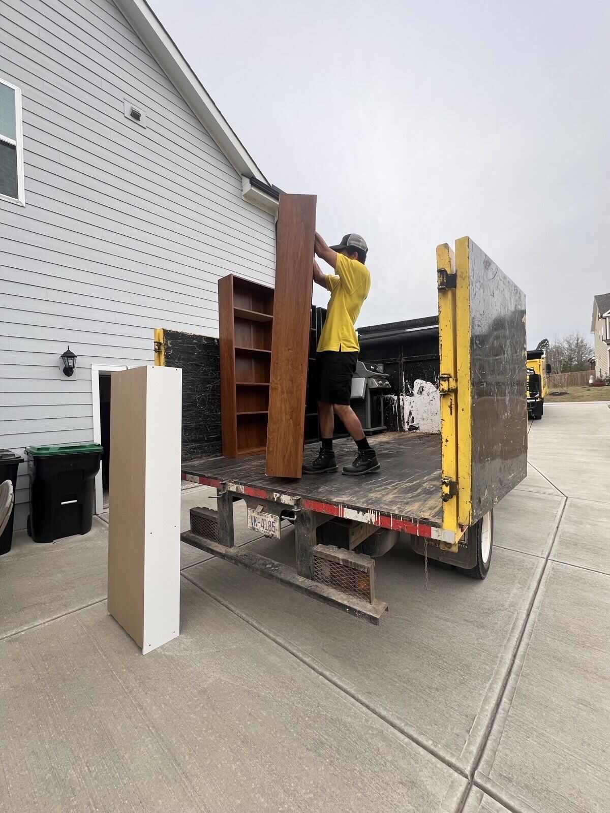 Professional junk removal team loading boxes and furniture into a truck outside a residential home.