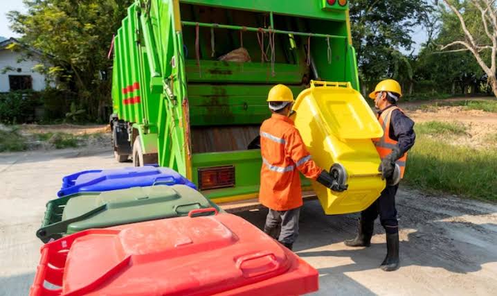 Professional waste collection team loading a residential trash bin into a collection truck in Charlottesville.