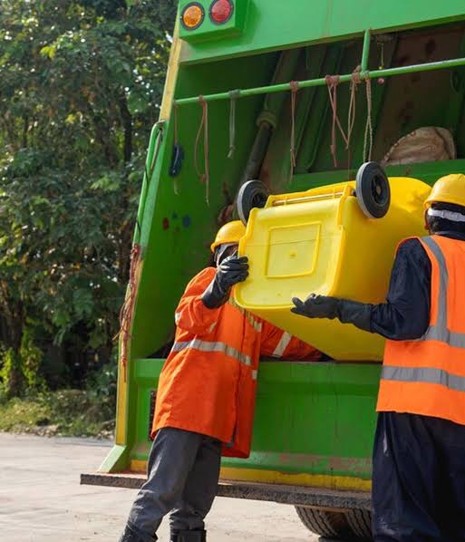 Waste collection crew emptying a residential trash bin into a garbage truck in Charlottesville.